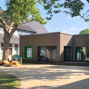 Neubauten Kindergarten mit Holzfassade und großen Fenstern zum Außengelände